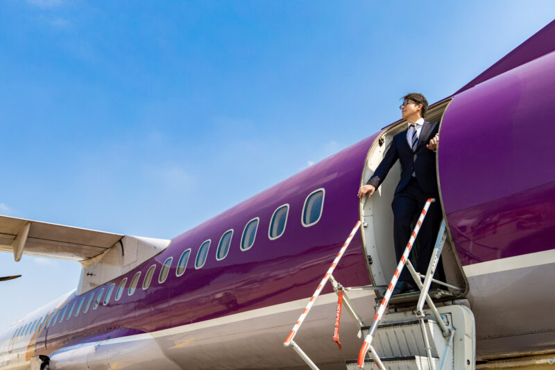 ピーチっぽいカラーリングの飛行機から颯爽と降りる男