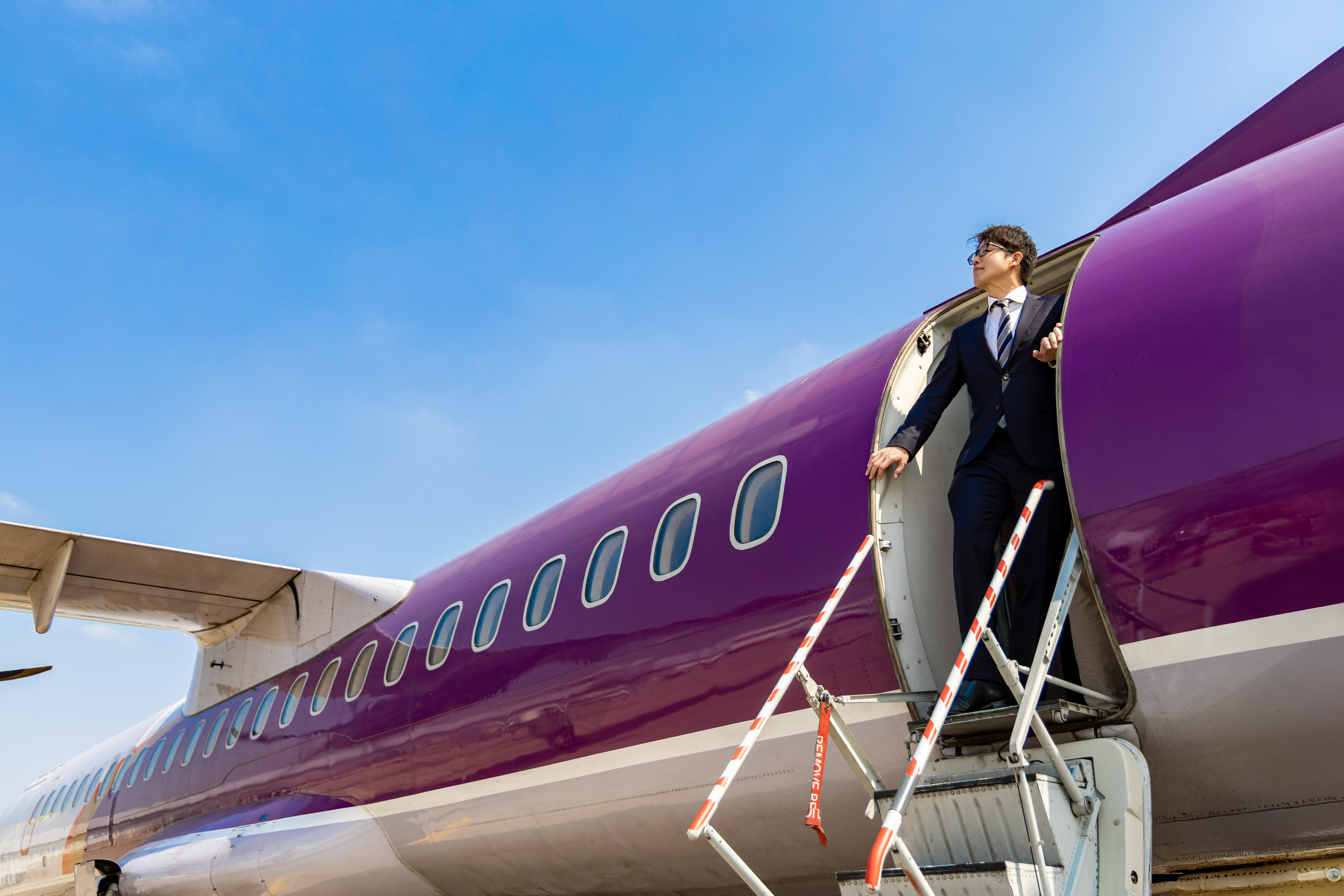 ピーチっぽいカラーリングの飛行機から颯爽と降りる男